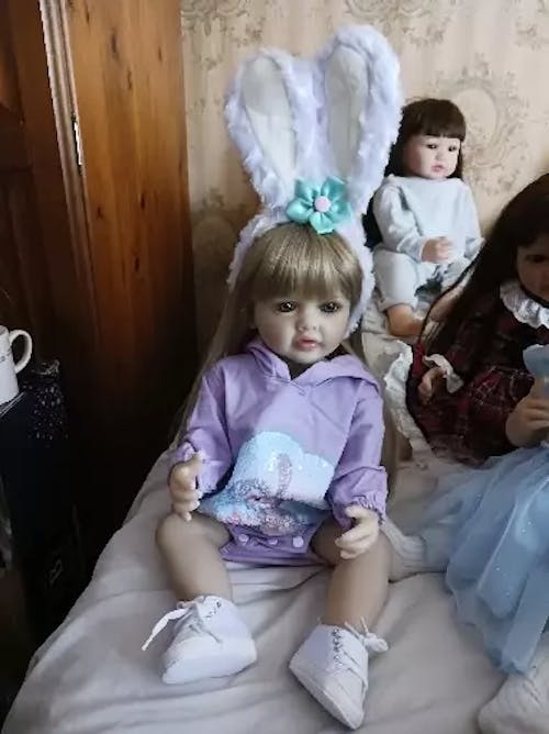 Bambina Reborn da 55 cm con occhi aperti capelli lunghi vestiti viola e fascia con orecchie da coniglio - Betty