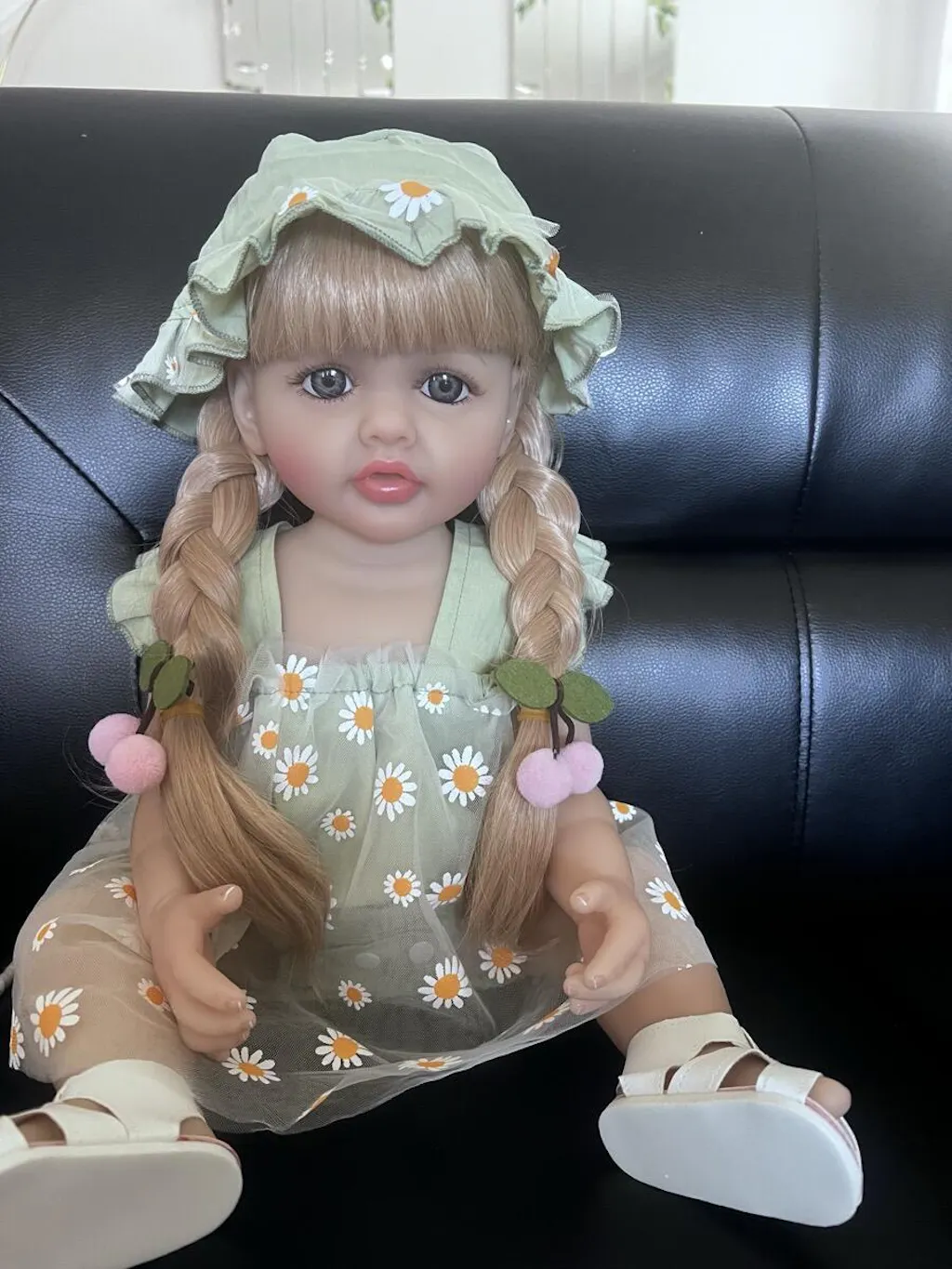 Bambina reborn Betty da 55 cm con occhi aperti e lunghi capelli biondi vestita con un abito verde a margherite
