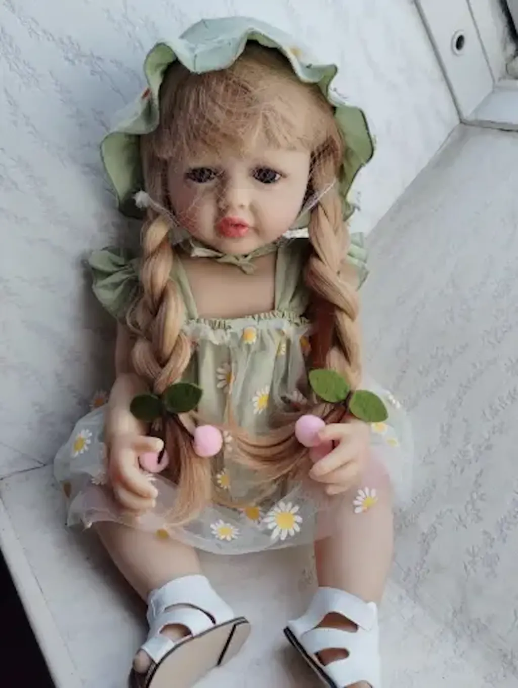 Bambina reborn Betty da 55 cm con occhi aperti e lunghi capelli biondi vestita con un abito verde a margherite
