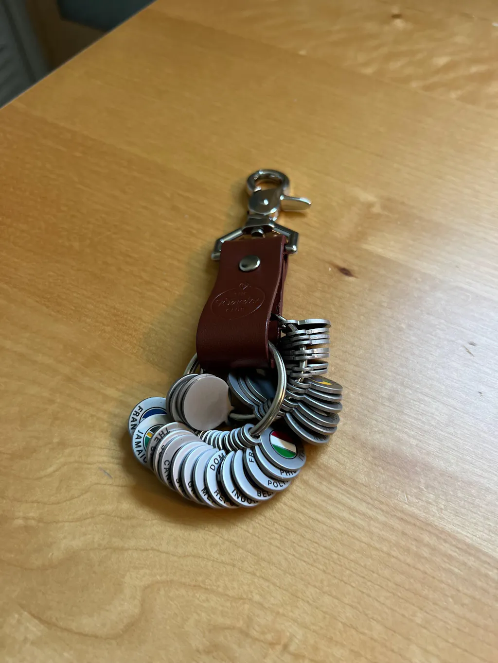 Customer's Wanderchain leather keychain loaded with country Tokens displayed on a wood table